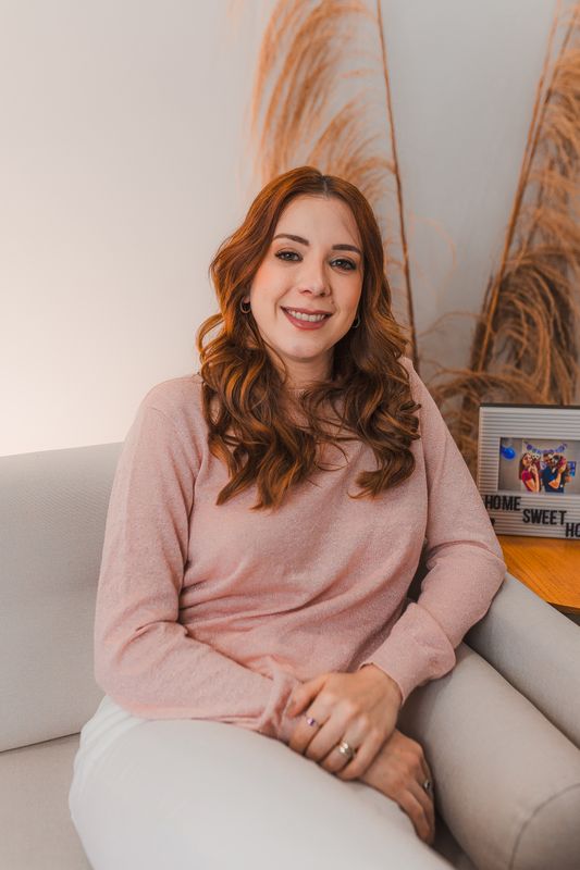 Dra. Maria Luiza Garbiere sentada no sofá, sorrindo